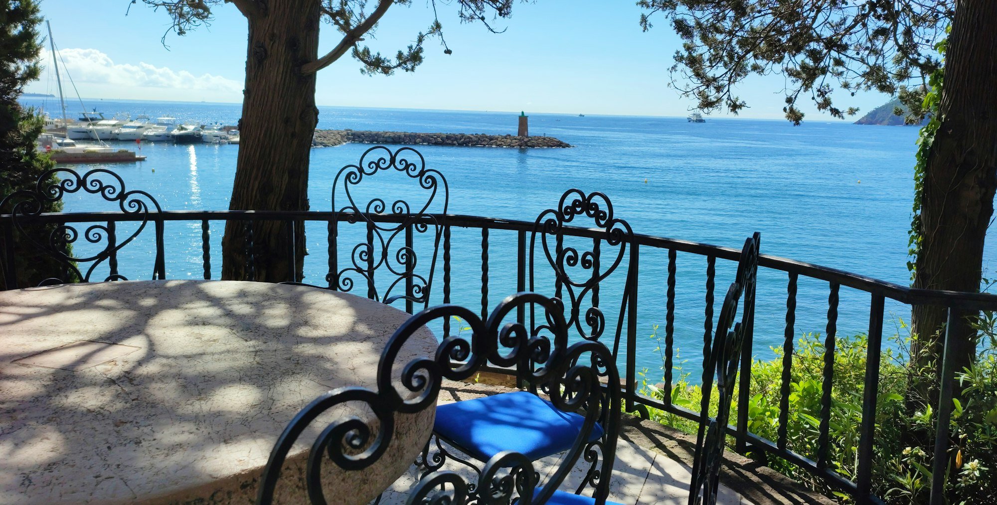 Table en fer forgé à l’ombre des pins, au-dessus de la mer