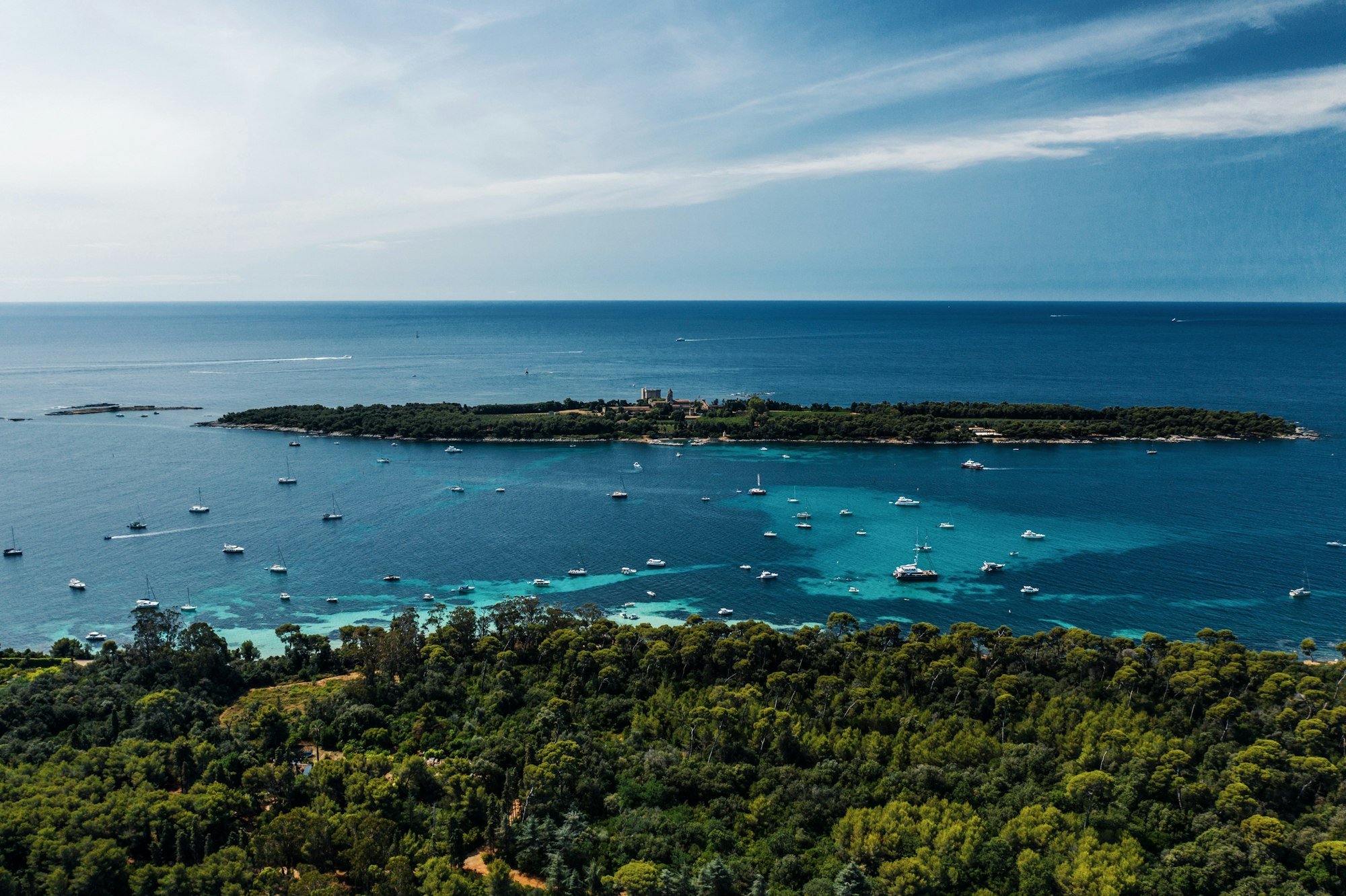 Une île boisée et des voiliers au mouillage dans l’eau turquoise